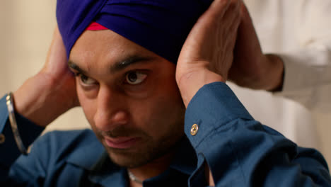 Close-Up-Studio-Shot-Of-Two-Sikh-Men-Using-Salai-Needle-When-Putting-On-Turban-Against-Plain-Background-1